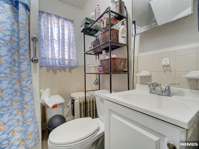 bathroom featuring vanity, toilet, and tile walls