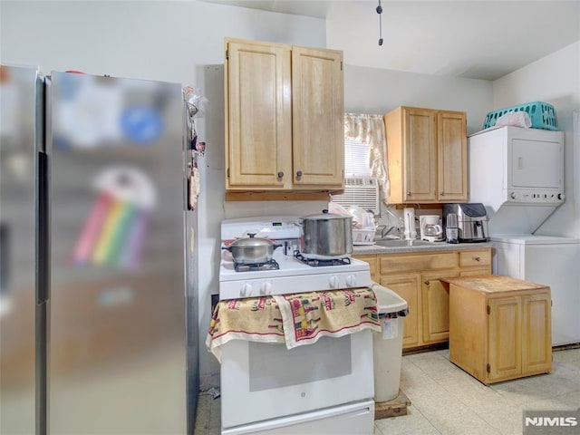 kitchen with sink, stainless steel fridge, light brown cabinetry, stacked washer and clothes dryer, and white gas range oven