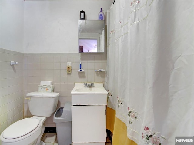 bathroom with vanity, toilet, and tile walls