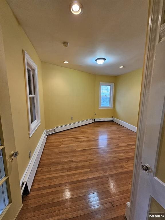 spare room with a baseboard heating unit and wood-type flooring