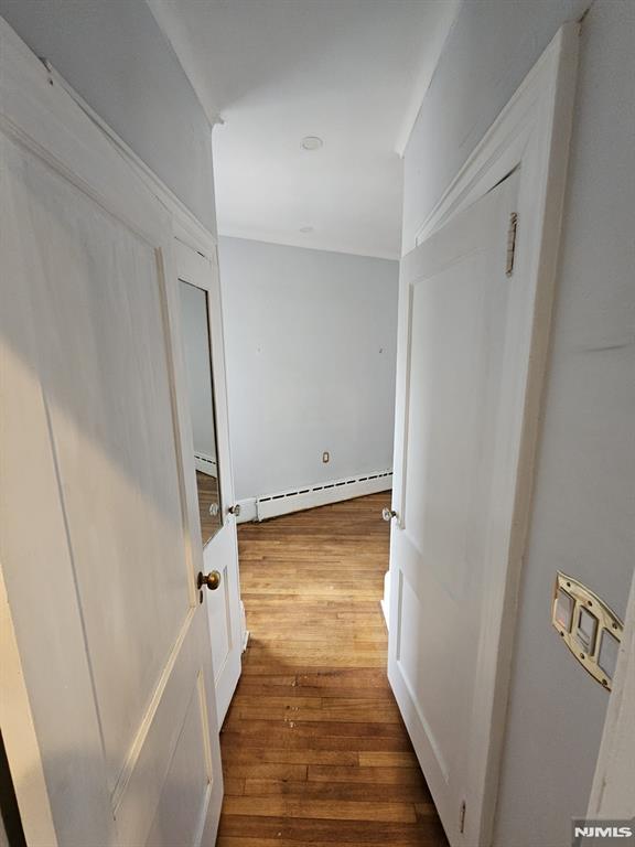 hallway with baseboard heating and dark hardwood / wood-style floors