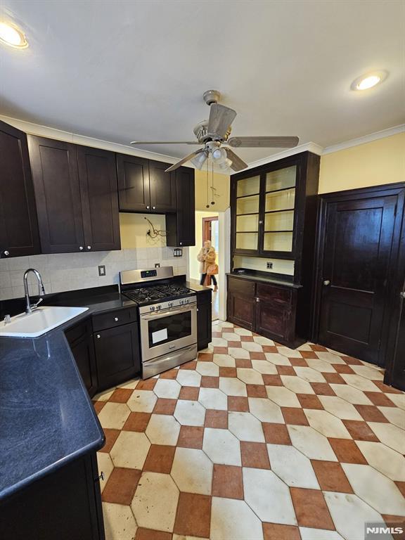 kitchen with sink, stainless steel gas range, ornamental molding, ceiling fan, and decorative backsplash