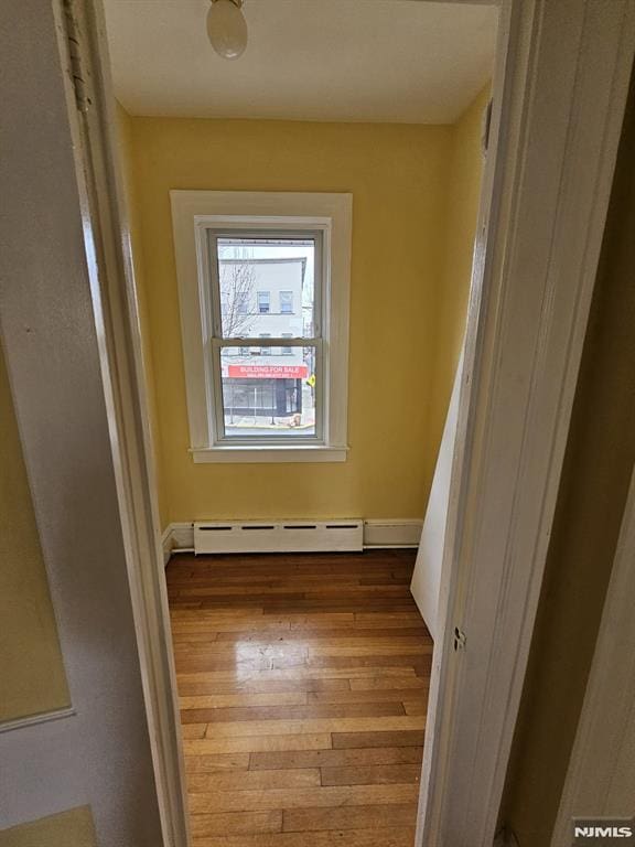 corridor with baseboard heating and wood-type flooring