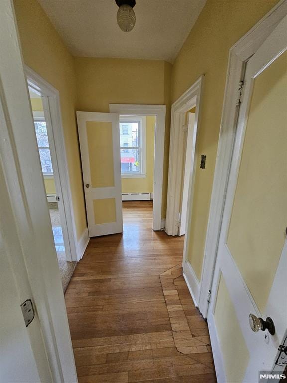 corridor featuring baseboard heating and hardwood / wood-style floors