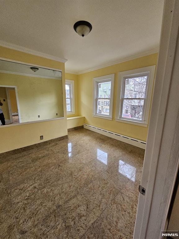 empty room featuring a baseboard heating unit and crown molding