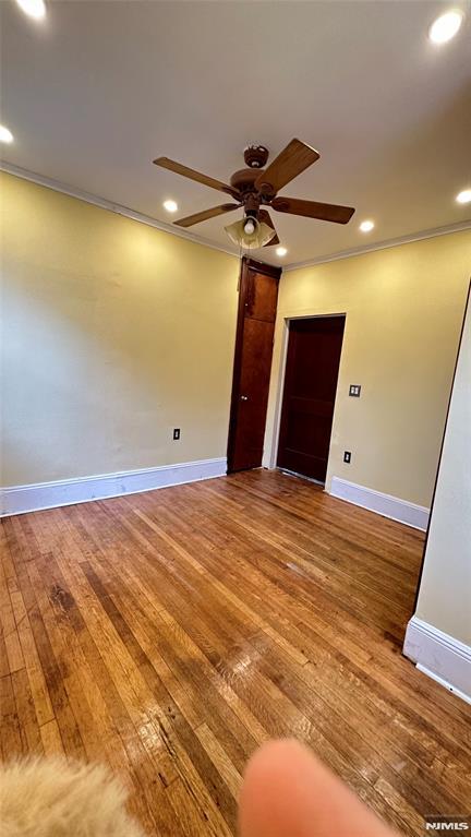 unfurnished room featuring ceiling fan, hardwood / wood-style floors, and crown molding