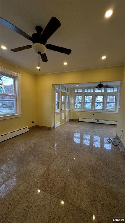 unfurnished living room featuring baseboard heating and ceiling fan