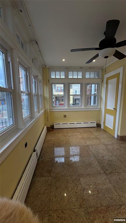 unfurnished sunroom featuring a wealth of natural light, ceiling fan, and a baseboard radiator