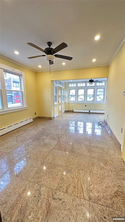 spare room with ceiling fan, baseboard heating, and crown molding