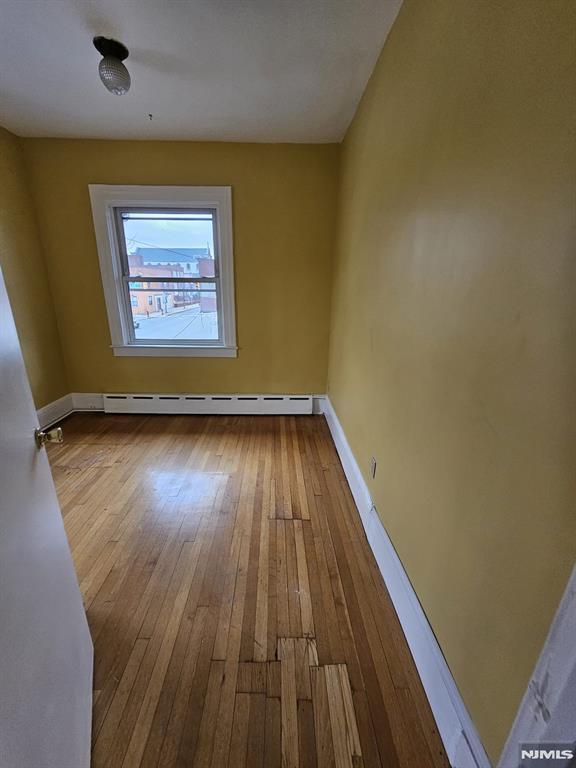 spare room with a baseboard heating unit and wood-type flooring