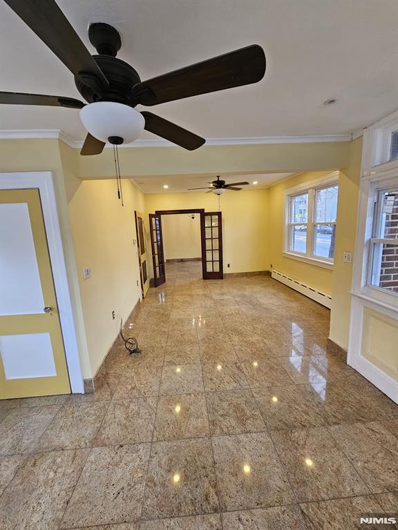 unfurnished room featuring ceiling fan, ornamental molding, and a baseboard heating unit