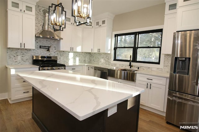 kitchen featuring tasteful backsplash, stainless steel appliances, white cabinets, a kitchen island, and hanging light fixtures