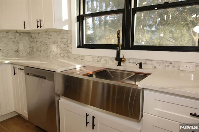 kitchen featuring white cabinetry, sink, stainless steel dishwasher, and light stone counters