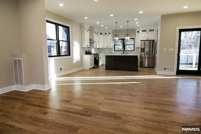 kitchen featuring a center island, hanging light fixtures, decorative backsplash, white cabinets, and appliances with stainless steel finishes