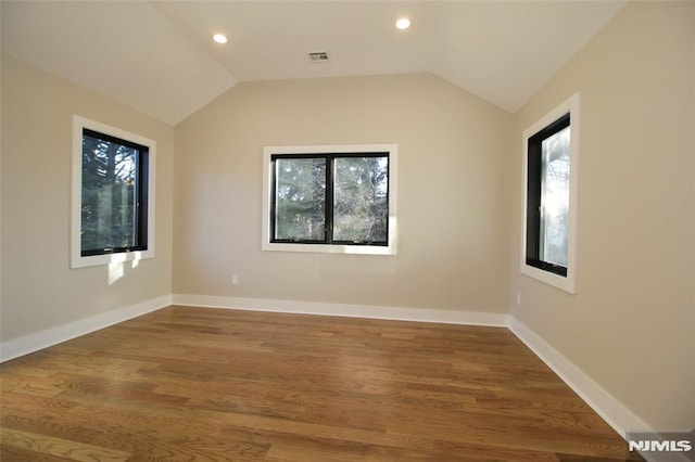 spare room with hardwood / wood-style floors, vaulted ceiling, and a healthy amount of sunlight