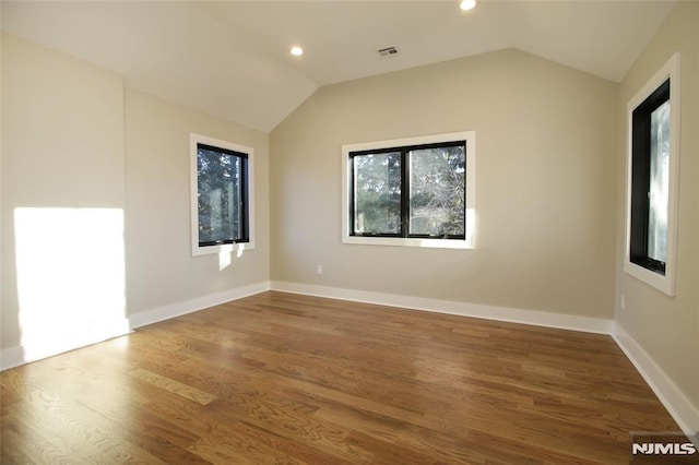 spare room featuring lofted ceiling and hardwood / wood-style flooring