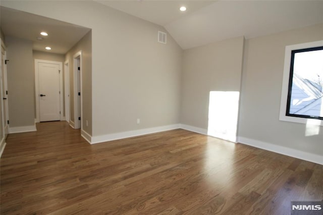 empty room with dark wood-type flooring and vaulted ceiling