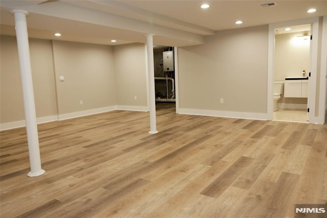 basement with light wood-type flooring and water heater