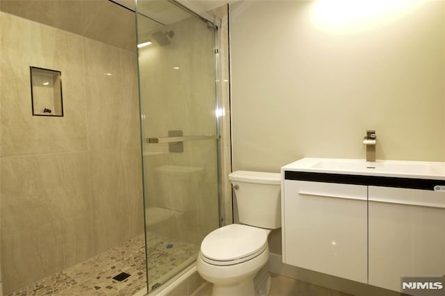 bathroom with a shower with door, vanity, and toilet