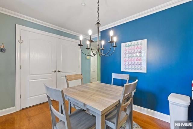 dining room with an inviting chandelier, hardwood / wood-style floors, and crown molding