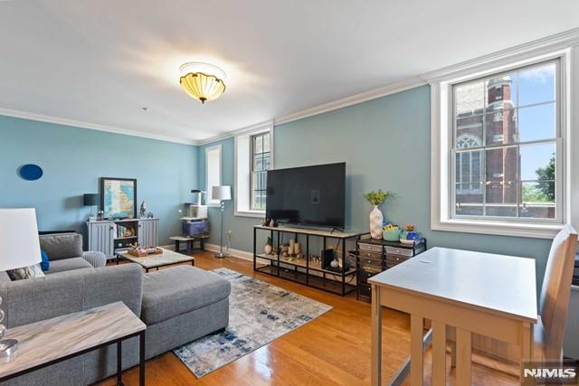 living room with a healthy amount of sunlight, hardwood / wood-style floors, and crown molding