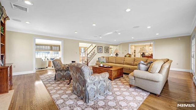 living room with ornamental molding and light hardwood / wood-style flooring