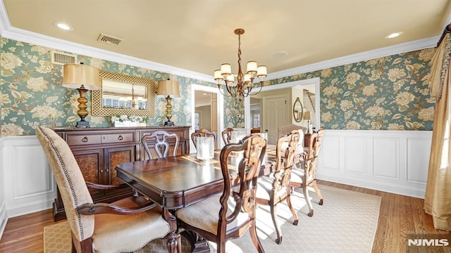 dining room with an inviting chandelier, hardwood / wood-style flooring, and crown molding