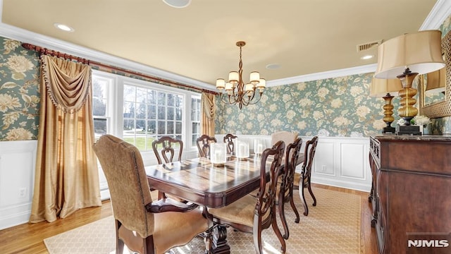 dining space featuring ornamental molding, light hardwood / wood-style floors, and a notable chandelier