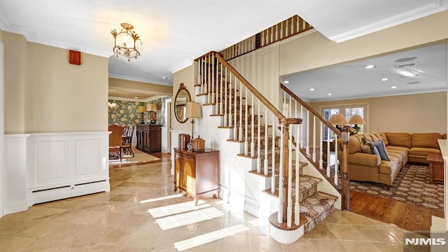 stairway with a notable chandelier, a baseboard heating unit, ornamental molding, and hardwood / wood-style floors