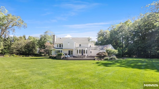 back of house featuring a lawn and a deck