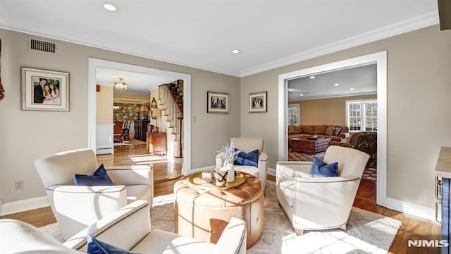 living area with ornamental molding and light hardwood / wood-style flooring