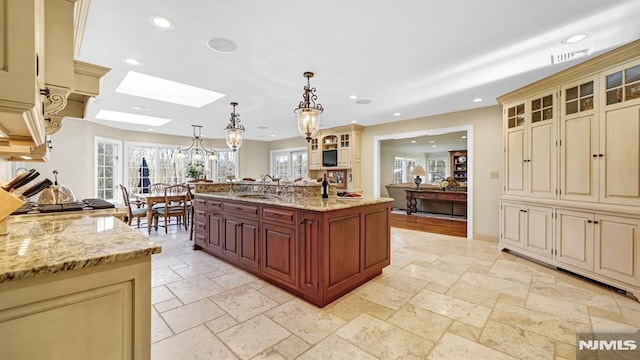 kitchen with hanging light fixtures, a skylight, and cream cabinetry