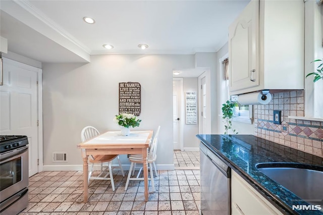 kitchen featuring crown molding, stainless steel appliances, white cabinets, and tasteful backsplash