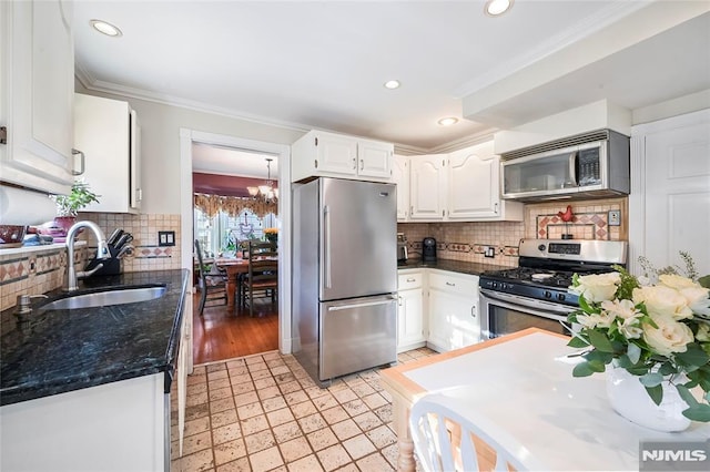 kitchen featuring stainless steel appliances, ornamental molding, decorative backsplash, sink, and white cabinetry