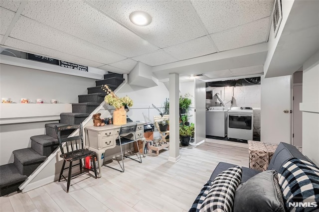 basement with washer / clothes dryer, a drop ceiling, and light wood-type flooring