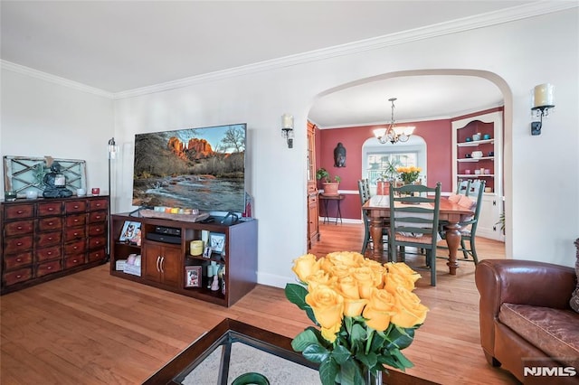 living room featuring hardwood / wood-style floors, a chandelier, built in shelves, and crown molding