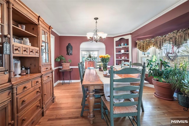 dining room with light hardwood / wood-style flooring, an inviting chandelier, and crown molding