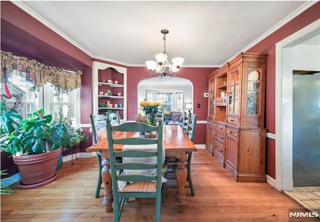 dining room featuring light hardwood / wood-style floors, an inviting chandelier, ornamental molding, and built in shelves