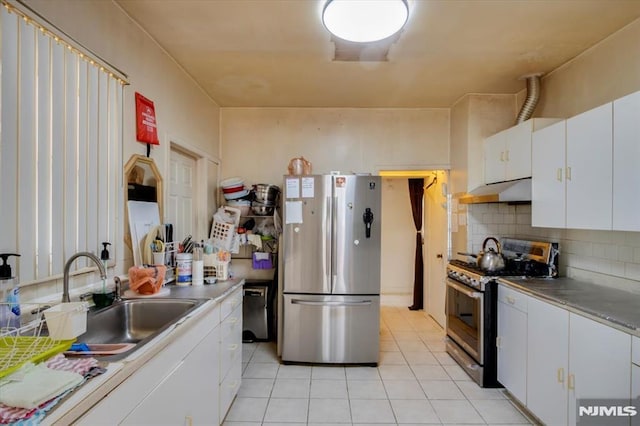 kitchen with stainless steel appliances, light tile patterned flooring, white cabinets, and sink