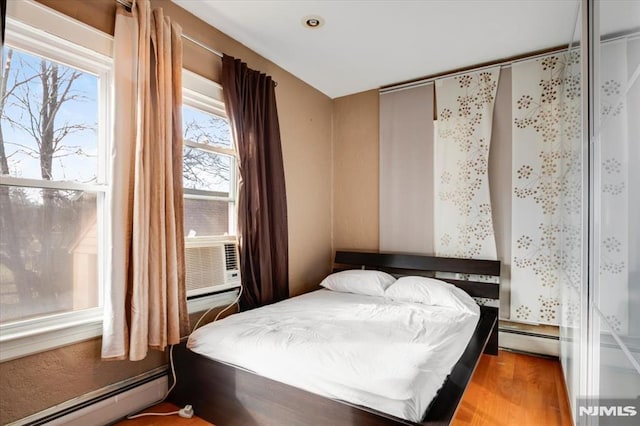 bedroom featuring cooling unit, a baseboard radiator, and wood-type flooring