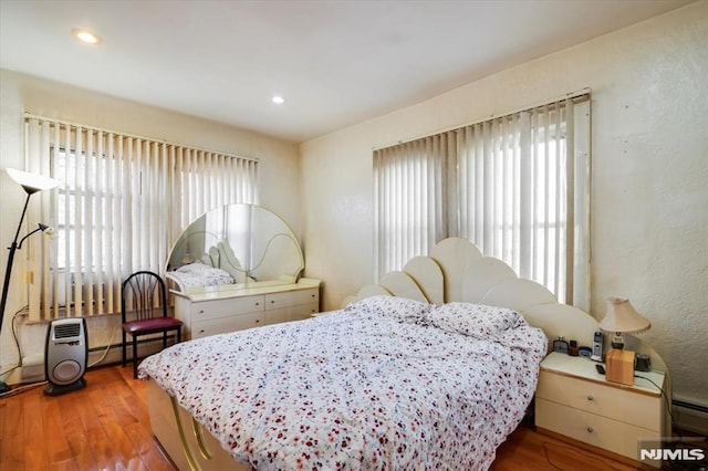 bedroom with baseboard heating and hardwood / wood-style floors