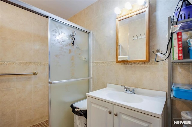 bathroom with tile walls, vanity, and a shower with shower door