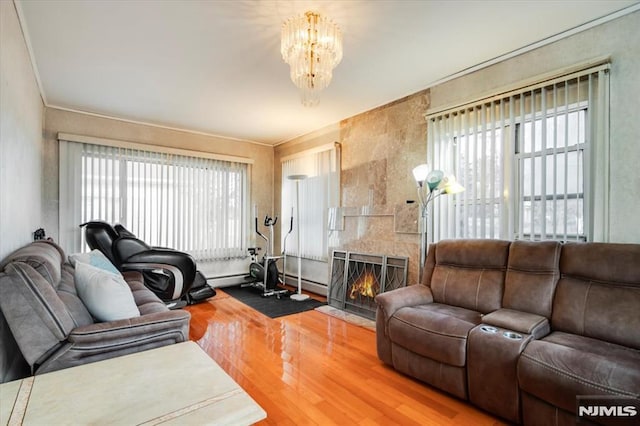 living room with a tile fireplace, a notable chandelier, wood-type flooring, and plenty of natural light