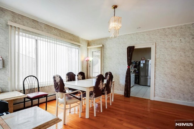 dining space with a baseboard heating unit, hardwood / wood-style floors, and a notable chandelier