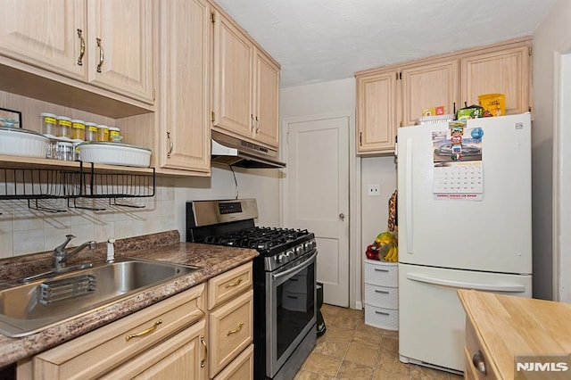 kitchen with sink, white fridge, light brown cabinetry, and gas stove