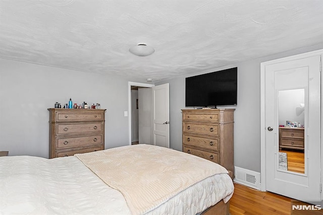 bedroom with a textured ceiling and hardwood / wood-style floors