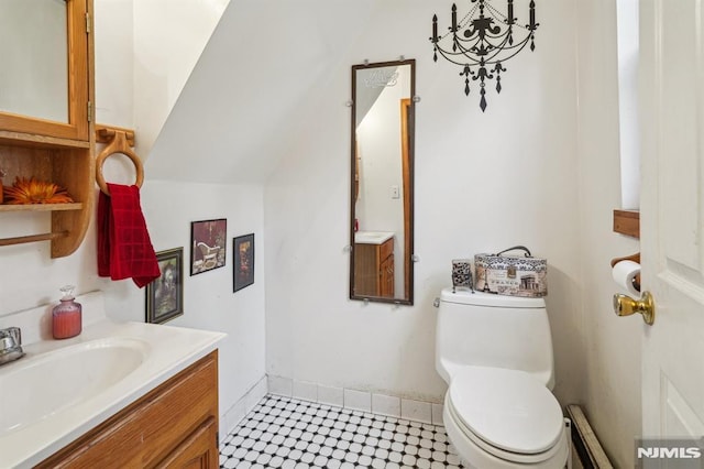 bathroom featuring toilet, lofted ceiling, vanity, and baseboard heating