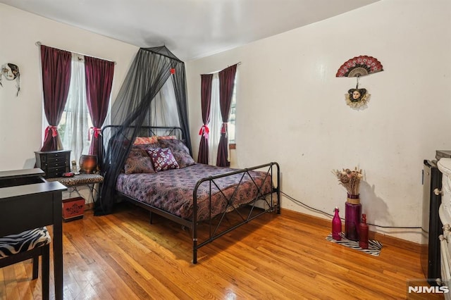 bedroom with wood-type flooring and multiple windows