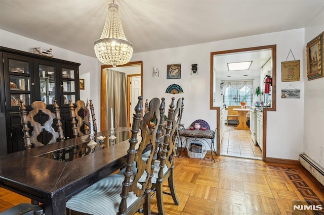 dining area featuring light parquet flooring, an inviting chandelier, and a baseboard heating unit