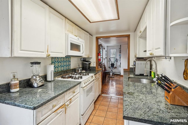 kitchen with white appliances, white cabinetry, sink, and light tile patterned floors